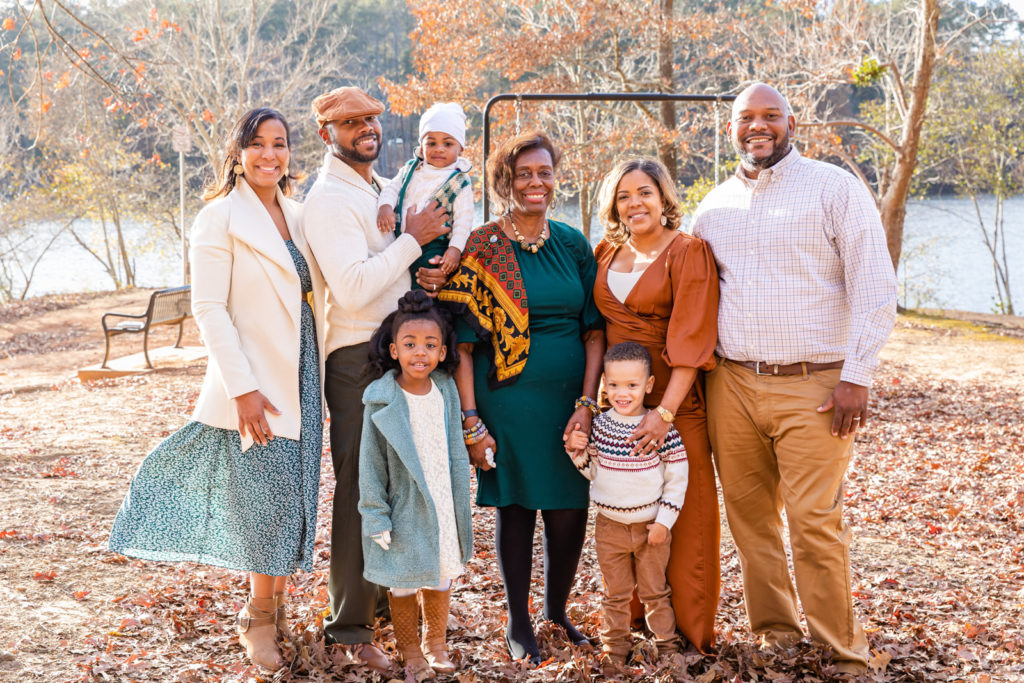 multi-generation family picture wearing brown white and green outfits standing in a park in Atlanta