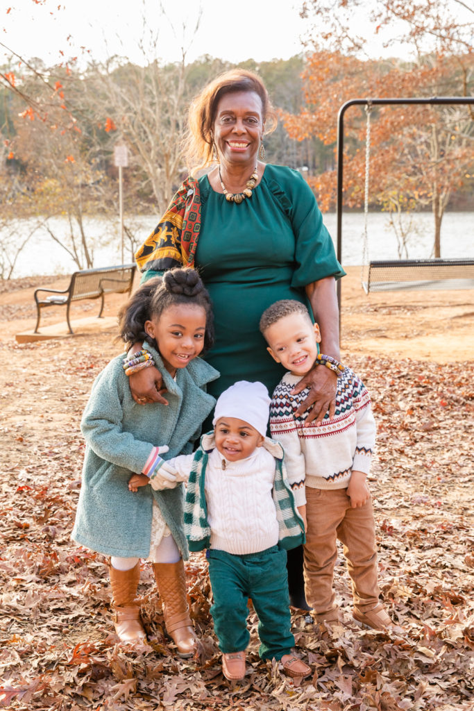 Grand mother with three grand children toddlers standing in a park in Brookhaven Atlanta GA during multi-generations photo session