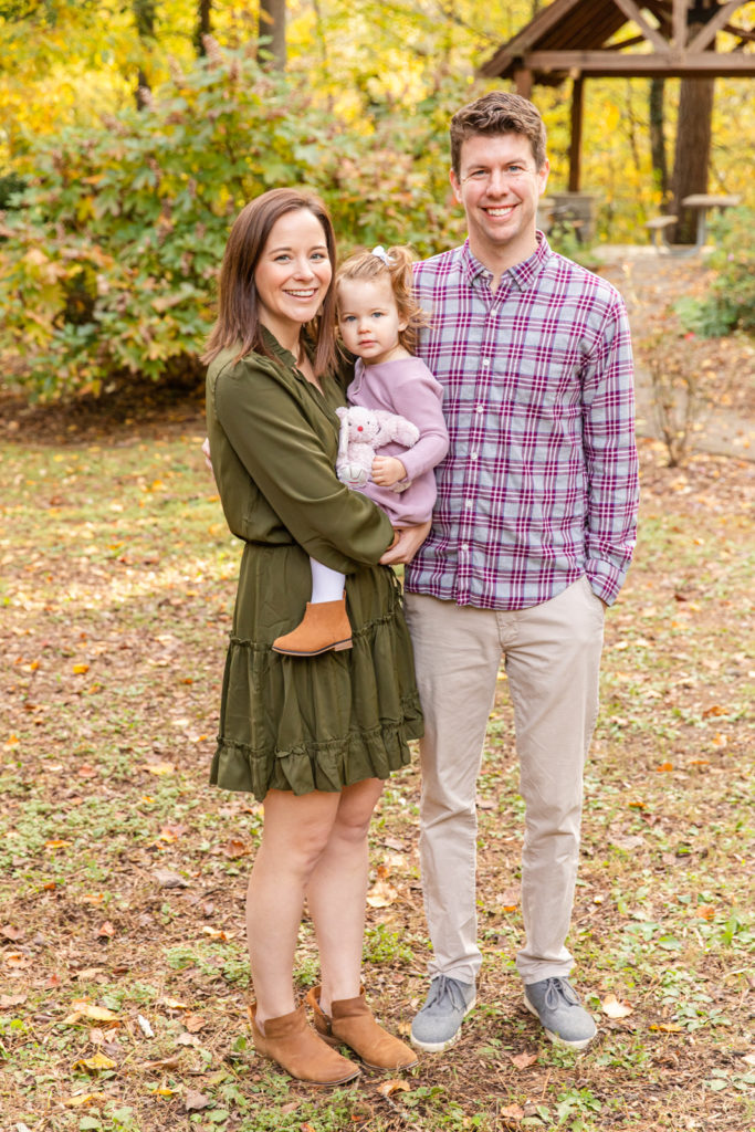 young parents with toddler daughter mum holding daughter and smiling in a park in Atlanta GA during fall mini-session with laure photography