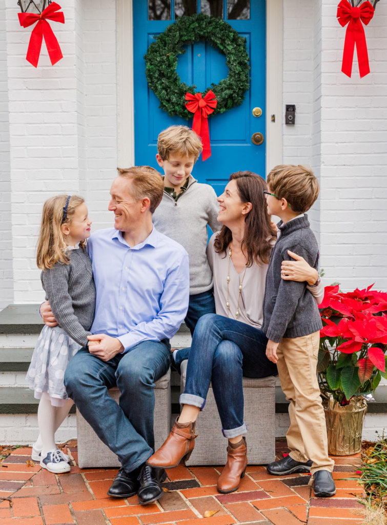 Lifestyle Family photo sitting looking at each other in front of house front door in Atlanta GA