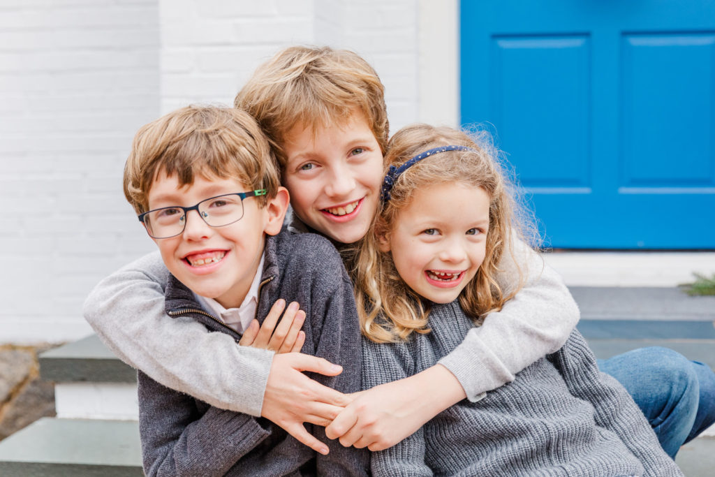 sibling portrait with children sitting and hugging in front of a house in GA