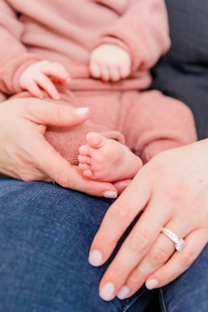 Details 3 month old baby foot in parents' hands during grow with me photo session
