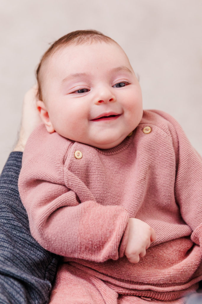 3 month old baby girl in pink outfit smiling by Laure photography