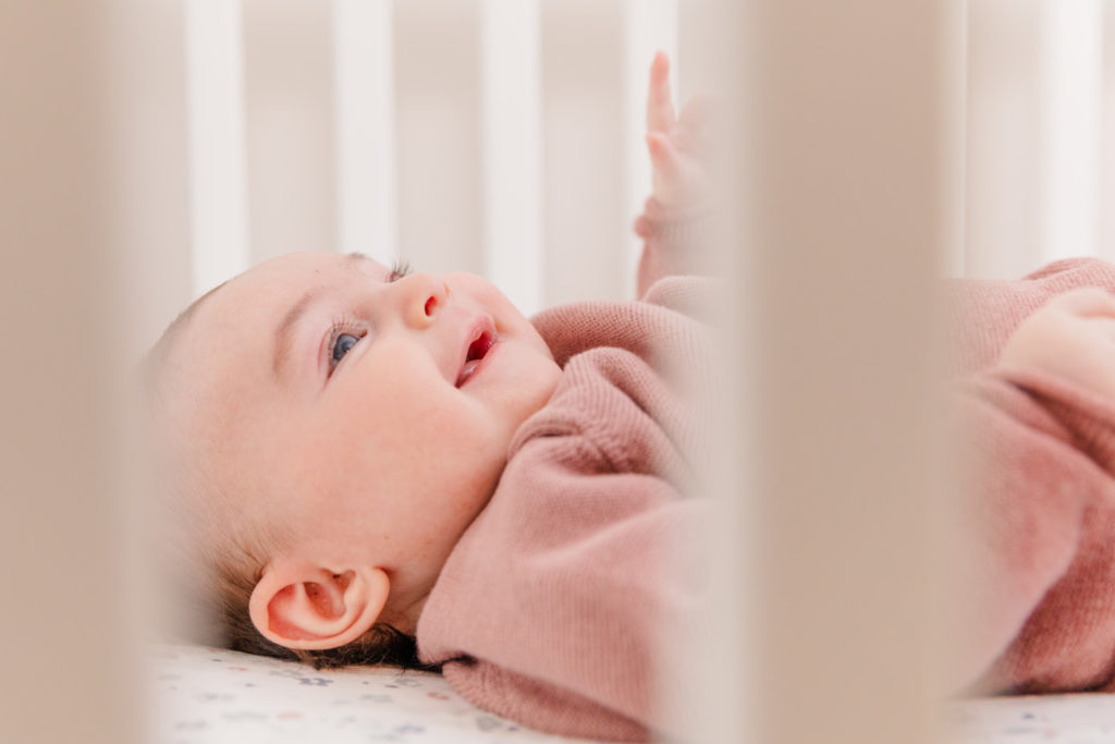 baby girl in her crib by lifestyle newborn photographer Laure photography