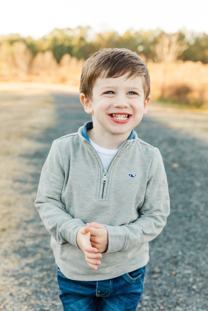 toddler in grey sweater laughing a a park path in Atlanta GA during portrait session