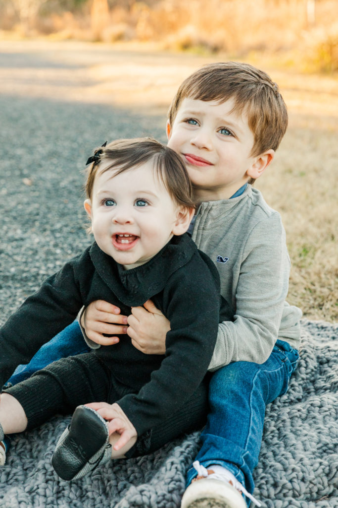 siblings toddler and baby sitting on a blanket in a park with atlanta photographer Laure Photography