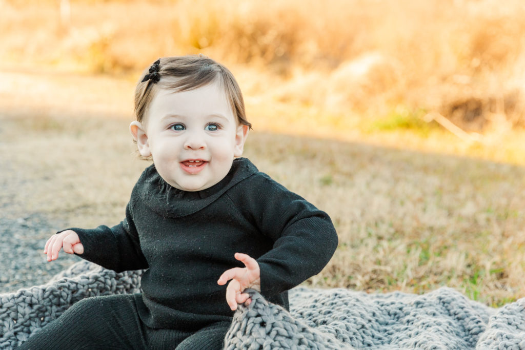 9 month old baby girl sitting on a grey blanket in a park with Atlanta photographer