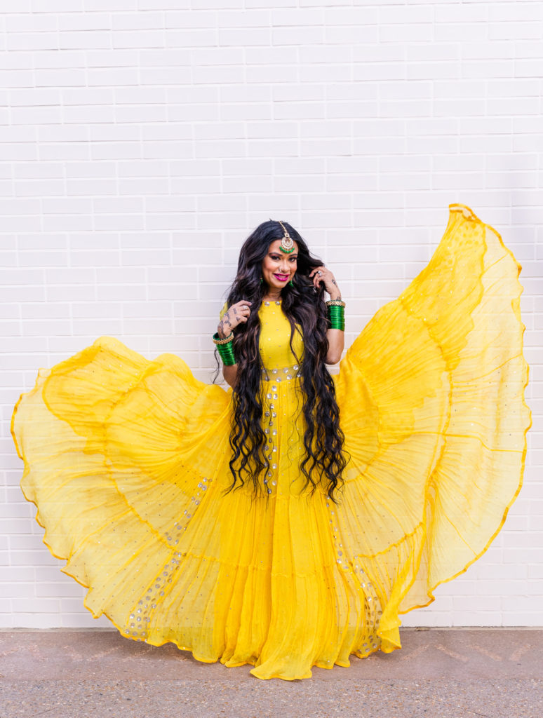woman with long dark wavy hair and cocktail yellow dress floating in the wind standing against a white wall in Atlanta GA with Laure Photography during branding session