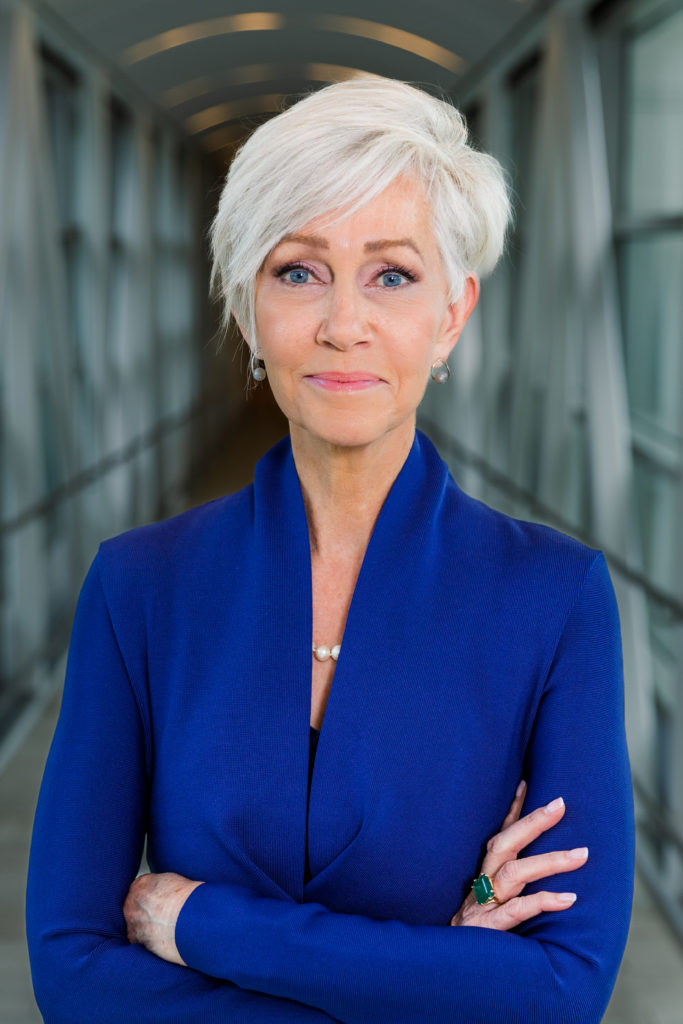 woman with gray hair in blue dress standing arms crossed during headshot session in Atlanta GA with Laure Photography