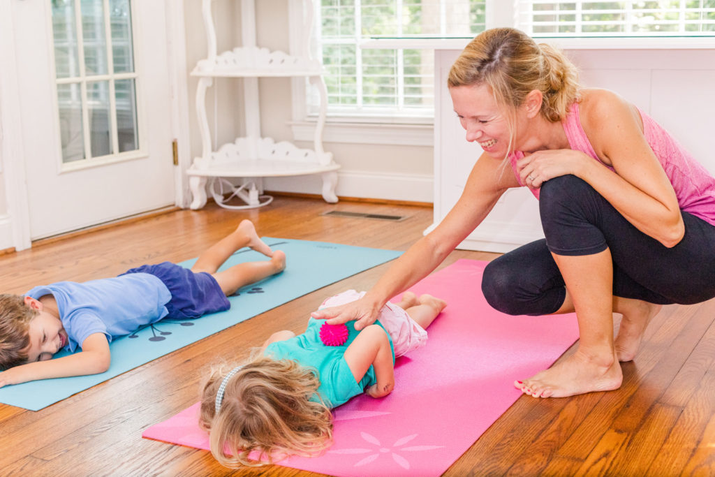teacher woman on black legging and pink to teaching yoga to a toddler on a mat during personal branding photo session in Atlanta GA with Laure Photography