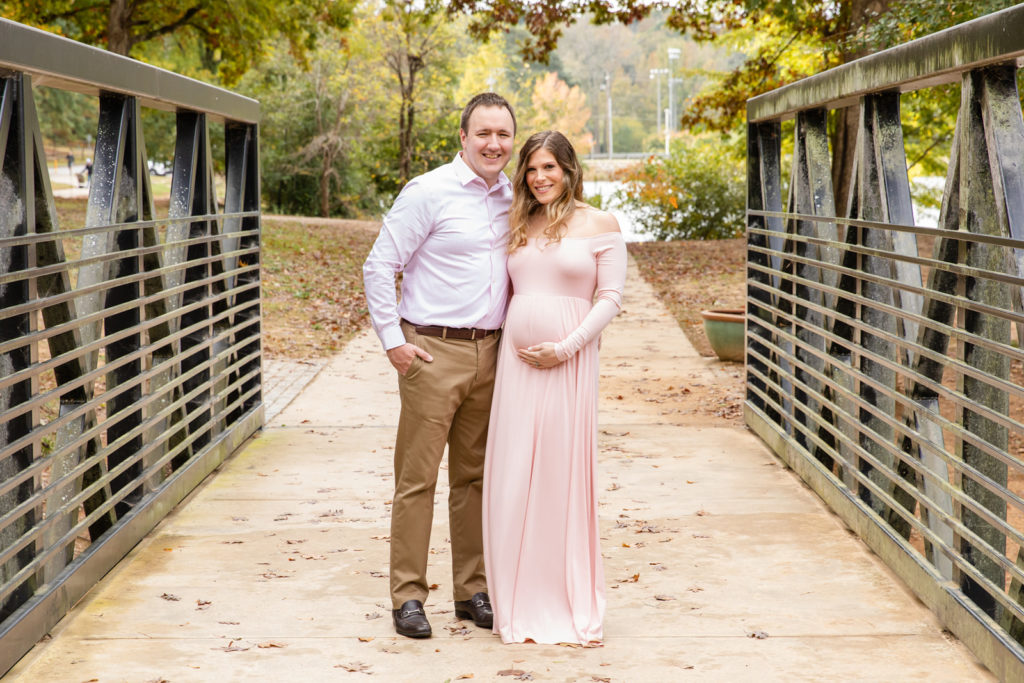 pregnancy photoshoot on a park bridge with long light pink dress with Laure photography