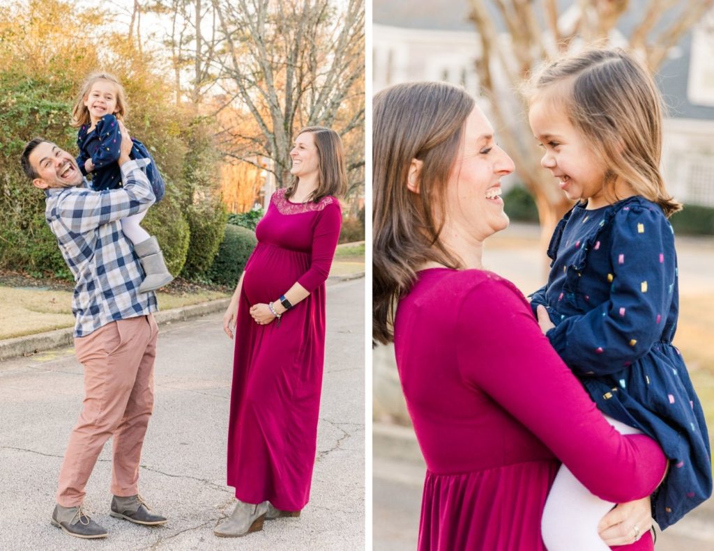 Lifestyle family pictures in the street mum in long pink maternity dress holding and smiling at her daughter and dad in beige pant and white and blue shirt holding toddler girl high with Atlanta photographer Laure Photography