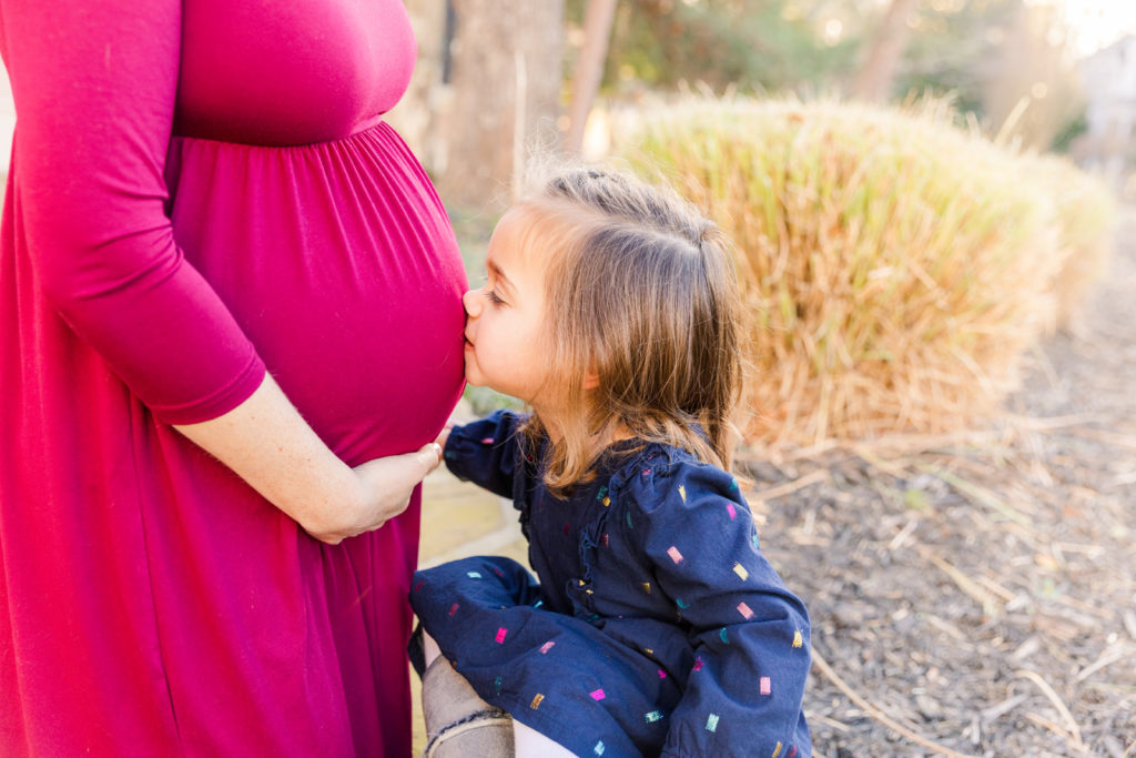 toddler girl kissing pregnant mum belly by Laure Photography