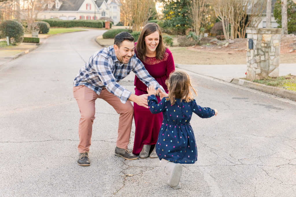 lifestyle family photoshoot with toddler running towards her parents in a Roswell GA street by Laure Photography