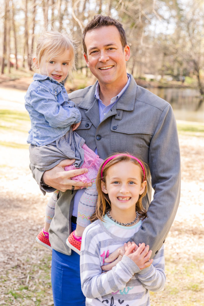 father with his daughters standing in front of a pond during photo session with Laure Photography Atlanta