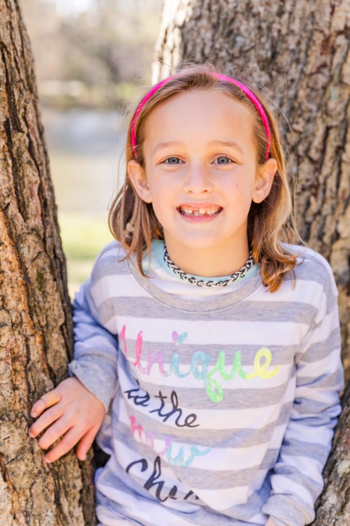 girl sitting on a tree during family photoshoot in a Buckhead Atlanta park with Laure Photography