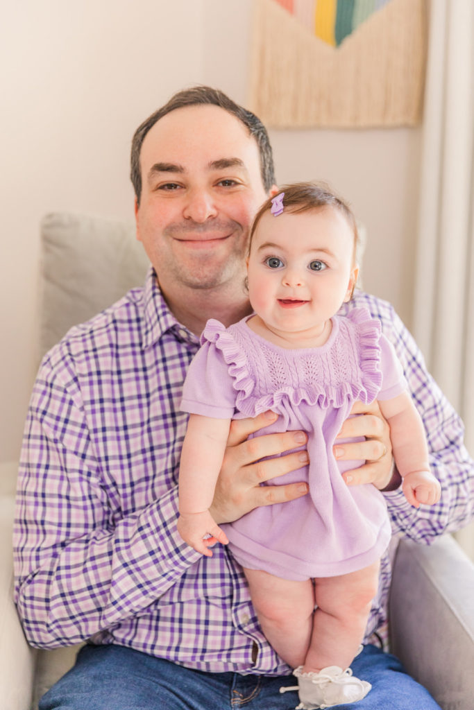 daddy and six month old baby girst standing on this knees with coordinated purple outfits with Atlanta Laure Photography