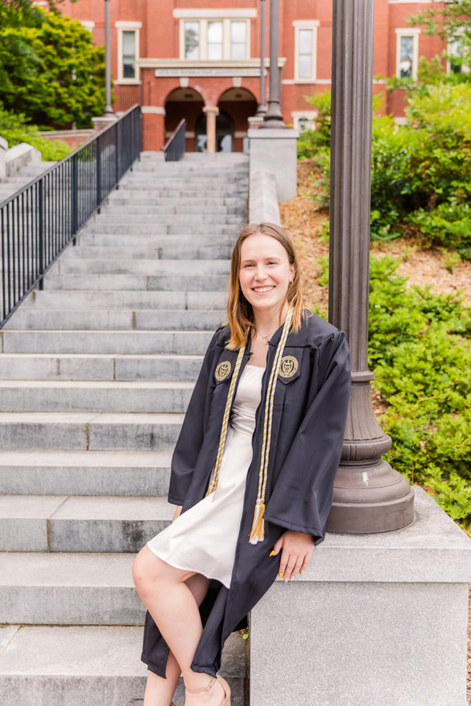 Georgia Tech college graduation graduate woman sitting on campus in cap & gown by Atlanta Photographer Laure Photography