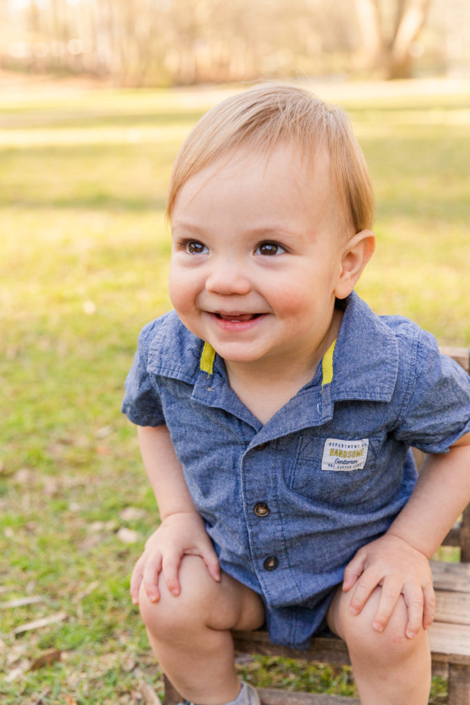 toddler boy laughing during family photo session sitting in Atlanta Buckhead Pond park with Laure Photography