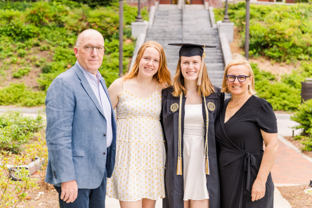 Graduate student woman with her family wearing her grown standing in front of stairs Georgia Tech Campus Atlanta by Laure Photography