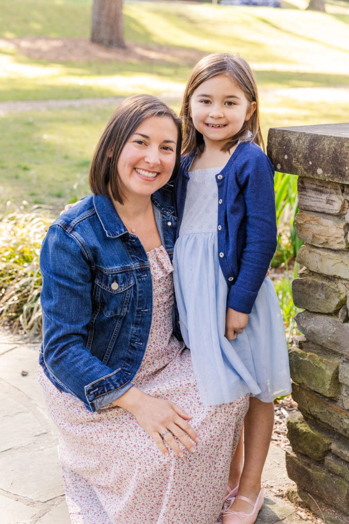 mom wearing pink and white flower dress and jeans jacket with daughter standing in light blue dress in a pond with Laure Photography Atlanta
