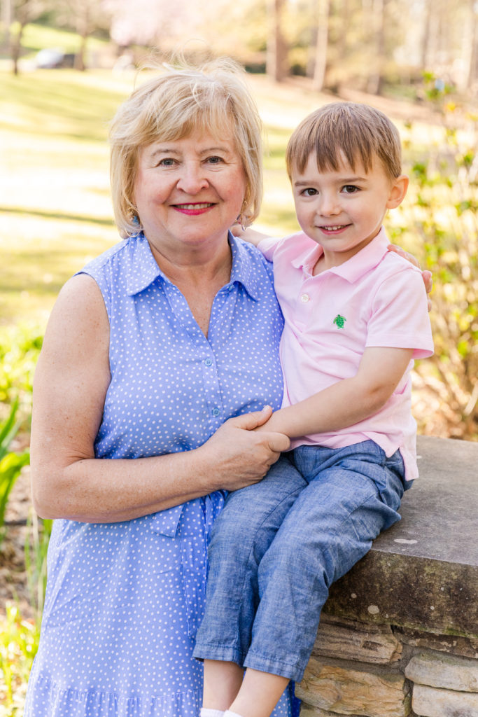 grand mother wearing blue and white dress and grand son in pink polo and jeans holding hands in a park with Laure Photography Atlanta