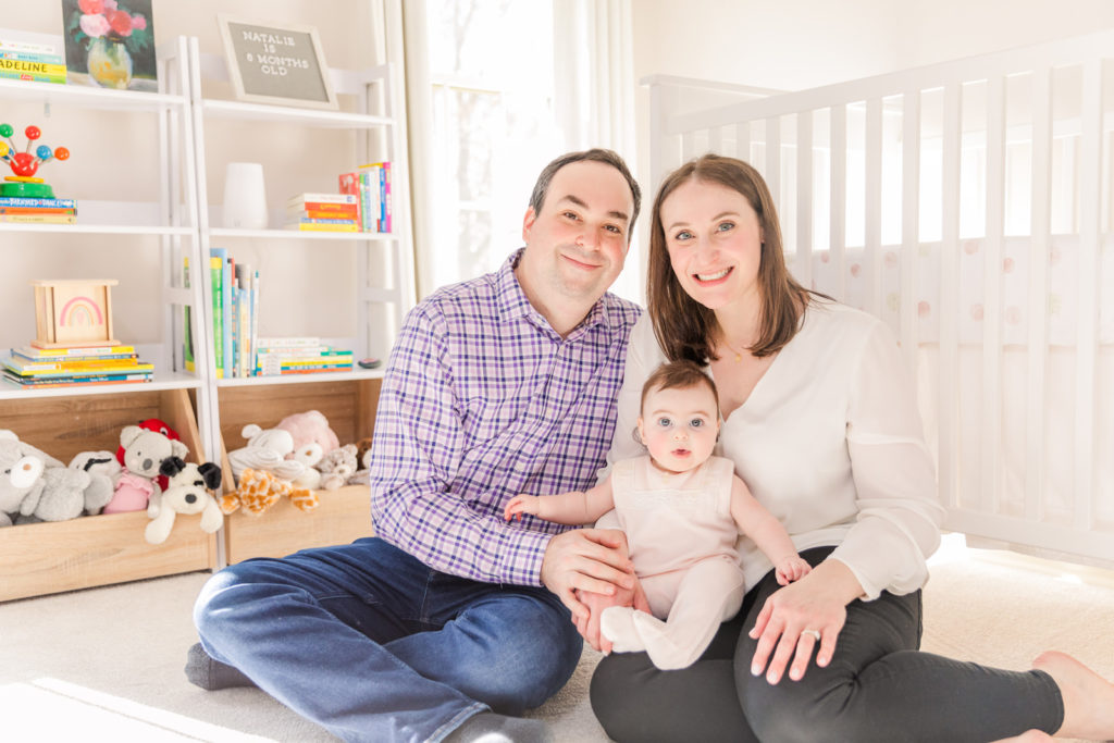 parents and baby girl sitting on the floor of the nursery with Atlanta Laure Photography