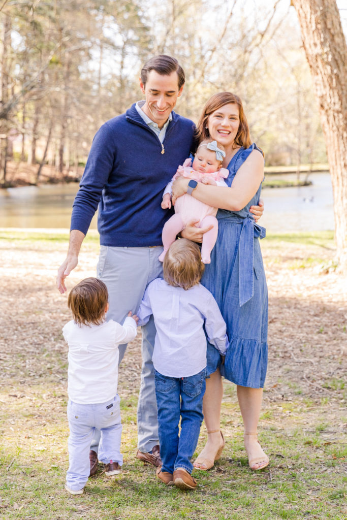 Lifestyle family pictures near a pond with a baby and toddlers family with blue outfits with Laure Photography Atlanta