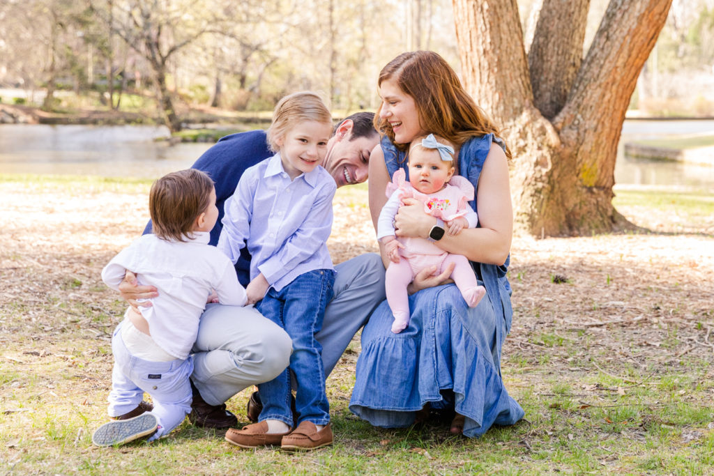 lifestyle family laughing pictures wearing coordinated blue clothes in a park near a pond with Laure Photography Atlanta