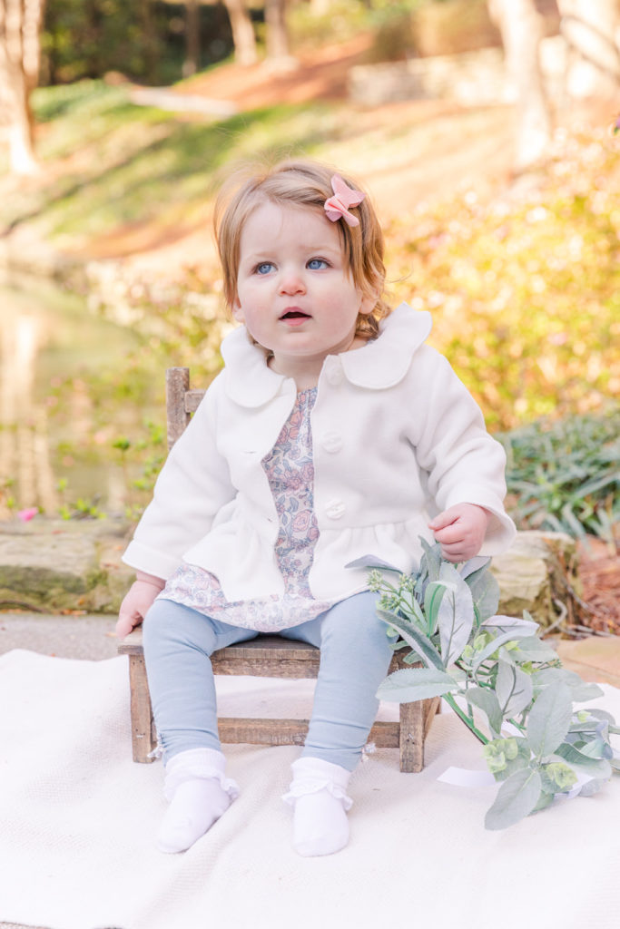 baby girl sitting on baby wooden chair on front in front a pond on a park in Dunwoody Atlanta with Laure photography