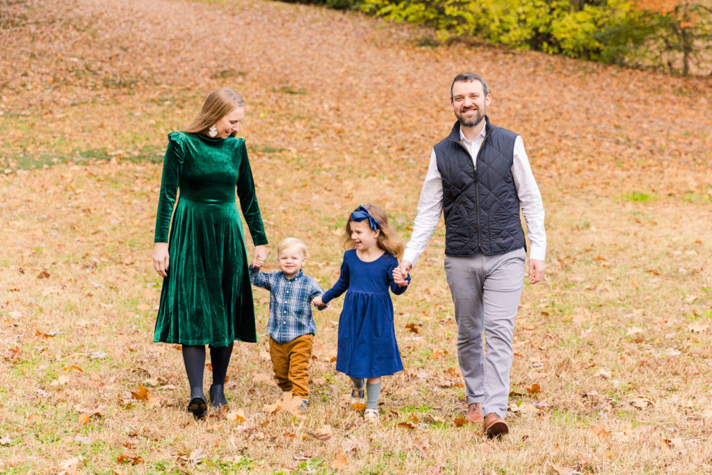 Family walking in a park in fall hands in hands looking at each other Atlanta GA park Laure photography lifestyle family photo session