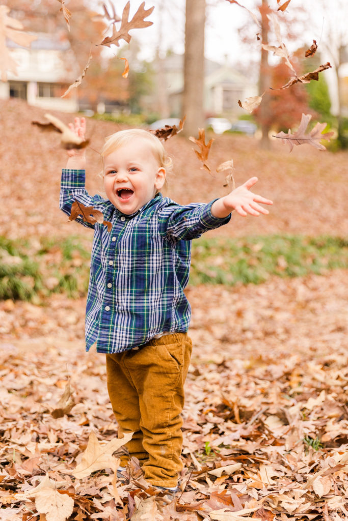 toddler boy laughing and throwing dead leaves in the air Atlanta GA park Laure photography lifestyle family photo session