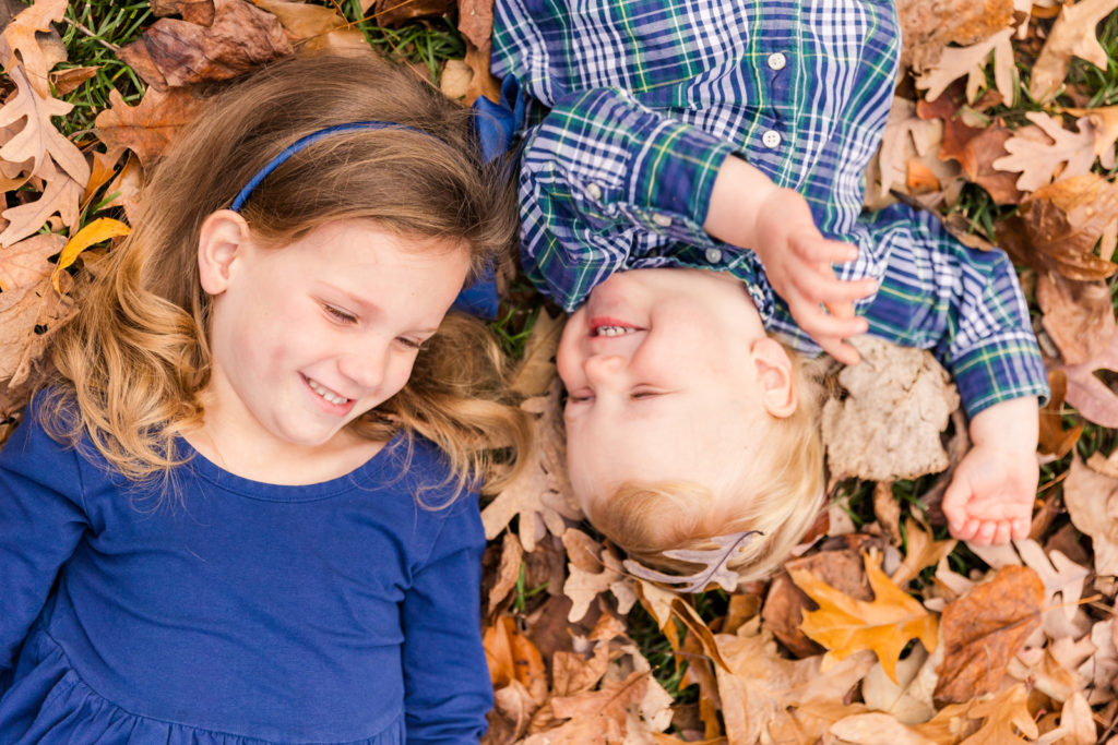 toddler siblings lying on a bed of dead leaves laughing Atlanta GA park Laure photography lifestyle family photo session