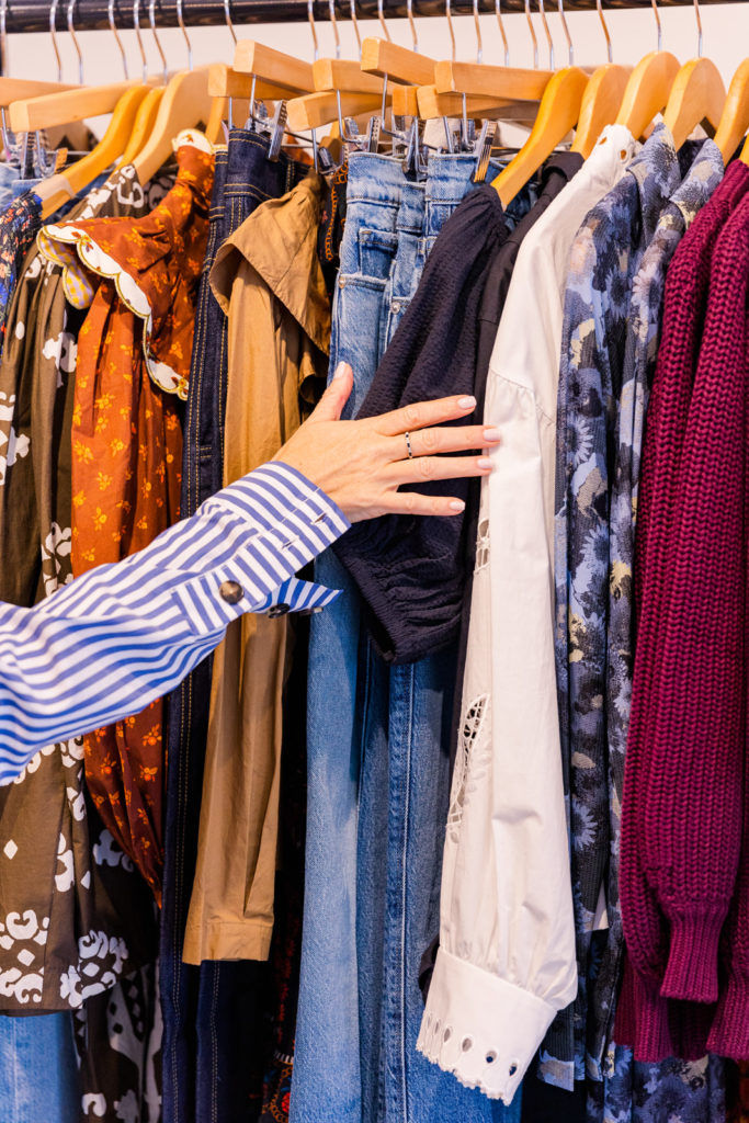 detail of woman's hand going through a rack of fashion clothes during personal branding photo session with Laure photography