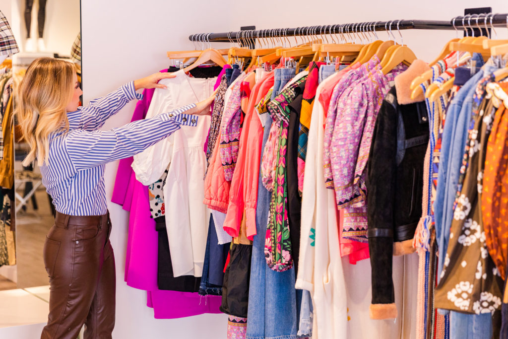 woman stylist from afar looking through a rack of fashion clothes