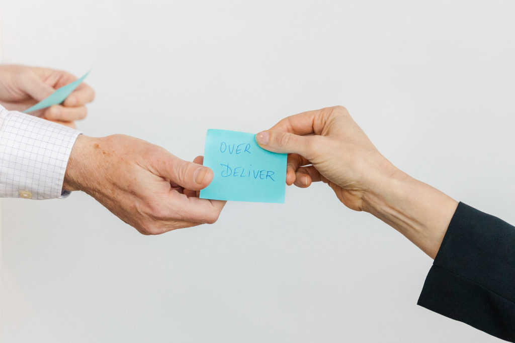 Detail of 2 persons holding a blue post it with over deliver written on it during Atlanta GA brand photo shoot with Laure photography
