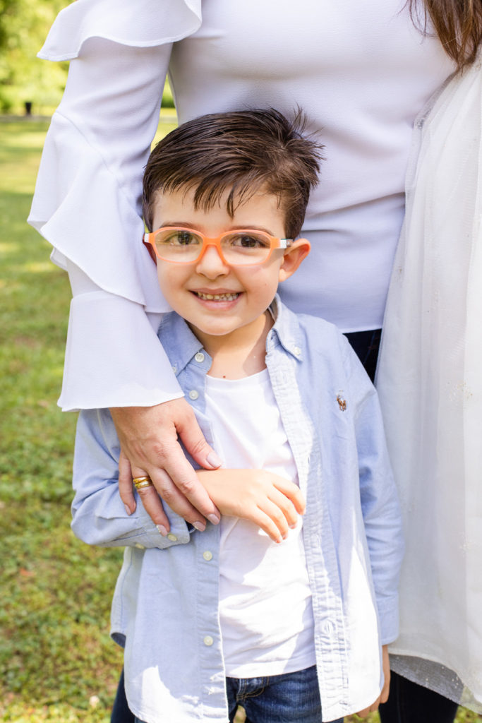toddler boy wearing a white tee-shirt and light blue Ralph Lauren shirt and blue jeans with orange classes during family photo session Laure photography