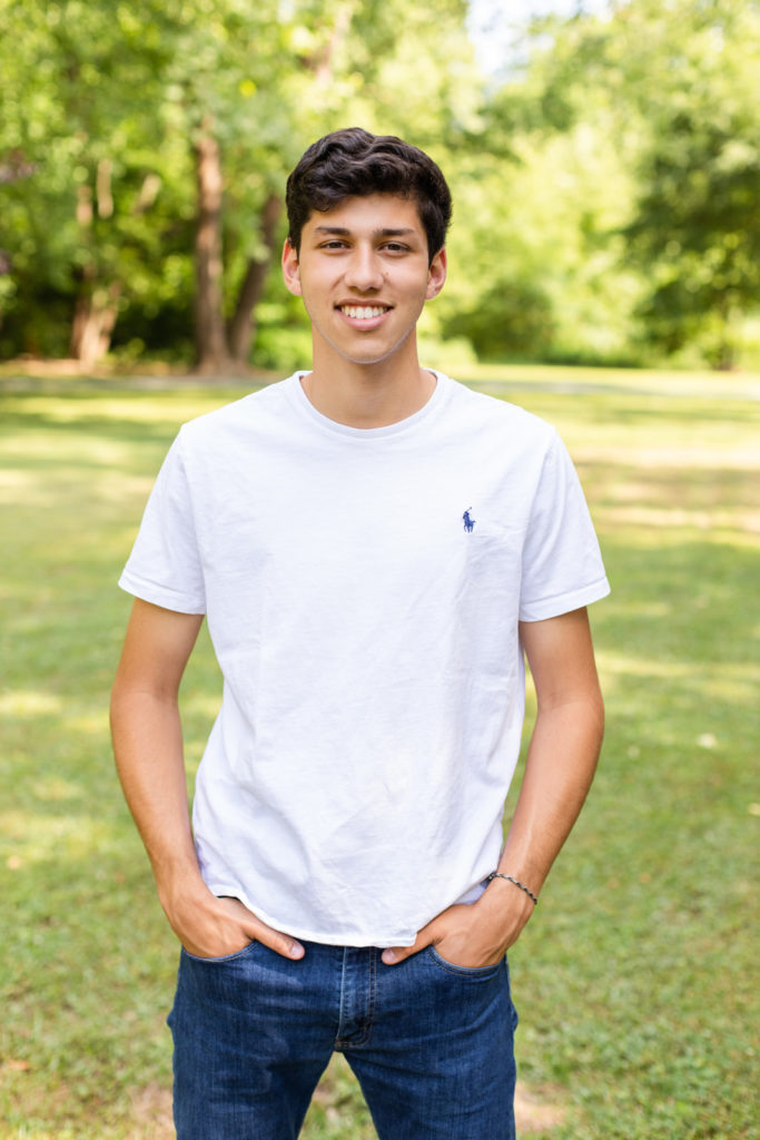 Senior boy photo session during spring in an Atlanta park wearing Ralph Lauren tee-shirt and blue jeans standing hands in pockets with Laure photography