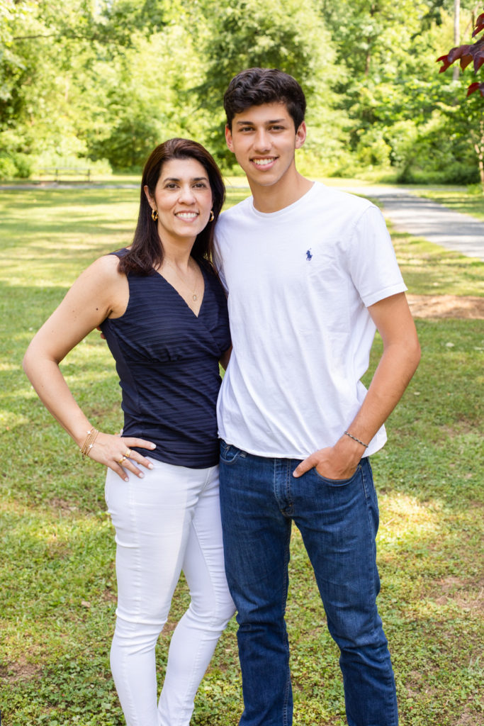 Mom and teenage boy mom wearing blue V shape top and white stretch jeans and teenage boy wearing white Ralph Lauren tee-shirt and blue jeans standing in a Sandy Spring park in GA Laure photography