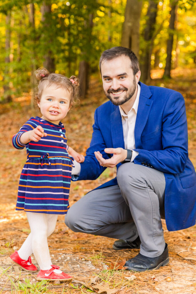 dad kneel down at toddler level in the woods during fall in Atlanta park
