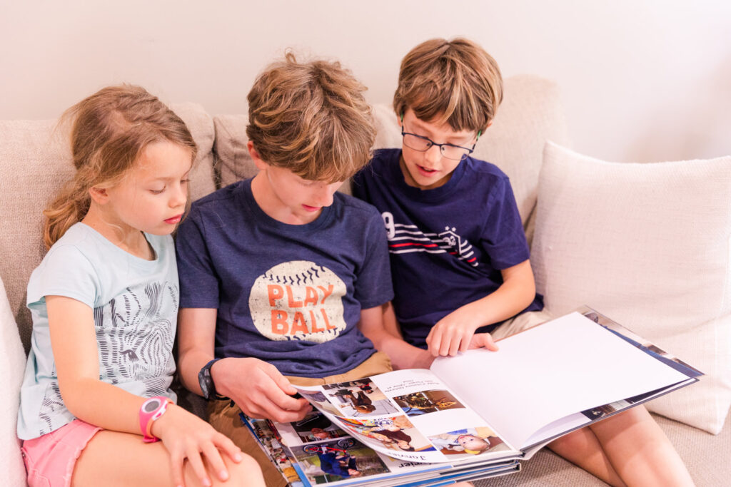 siblings reading together a family photo album lifestyle picture by Laure photography