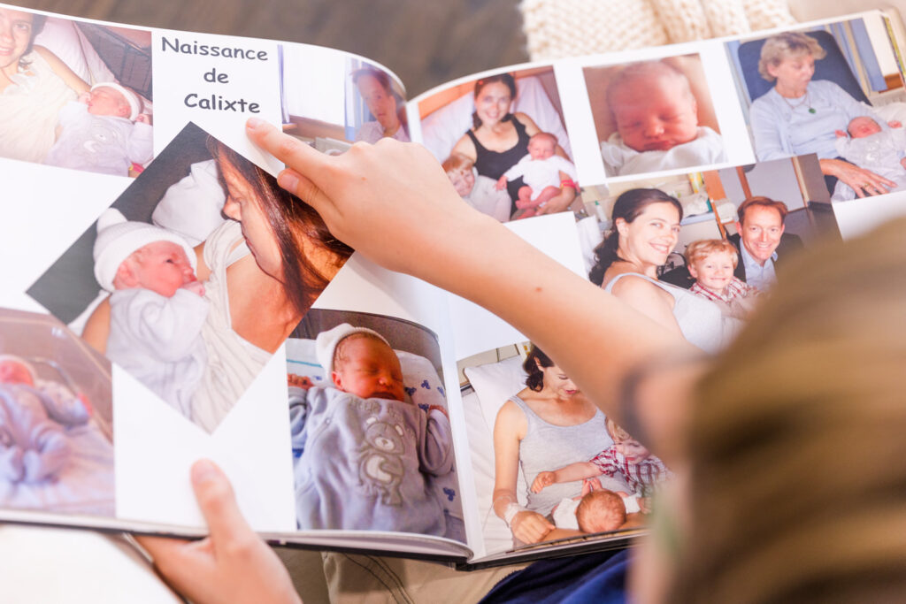 Child looking at a photo album with this newborn pictures by Laure photography