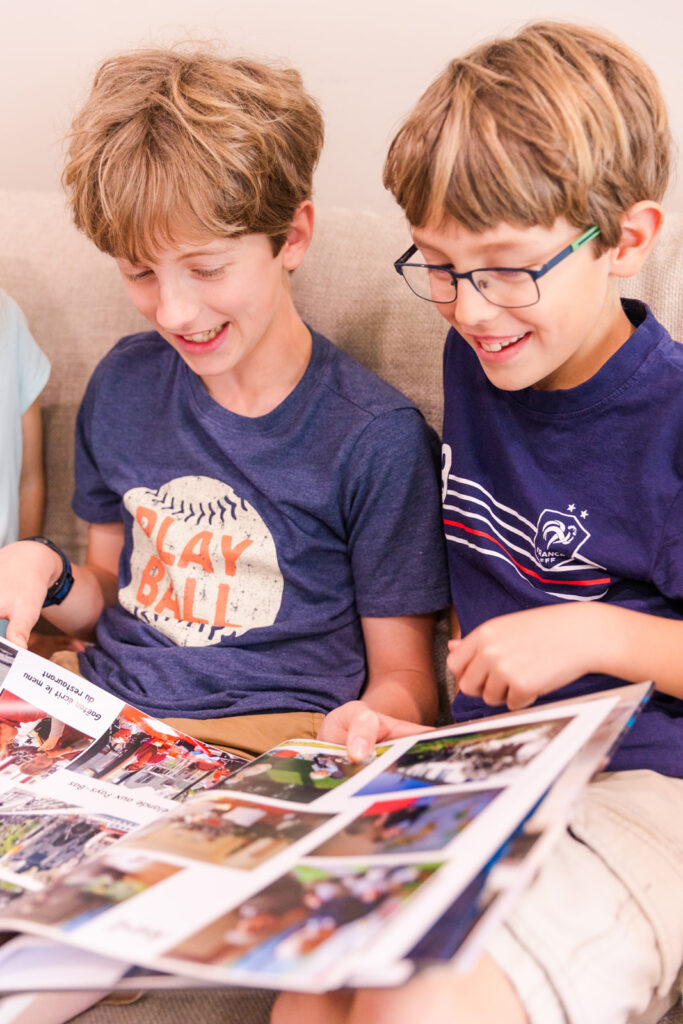 brothers laughing at a picture on photo album by laure photography