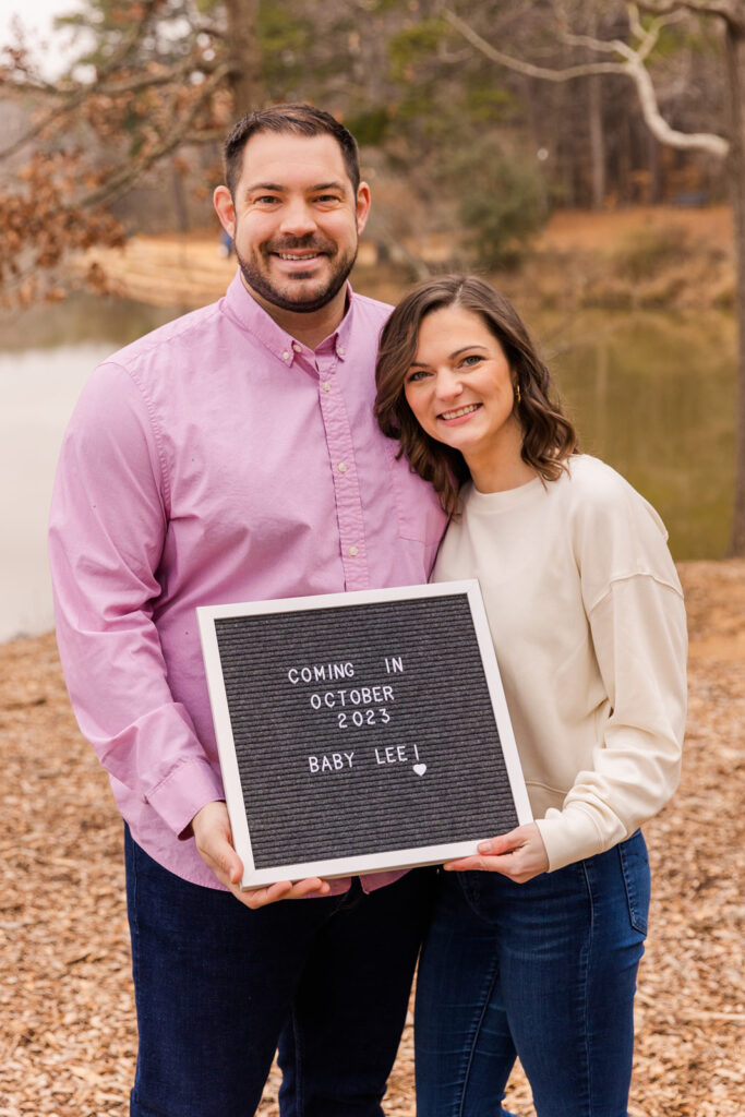 Couple holding a baby announcement sign in during photo session by Atlanta family photographer Laure Photography