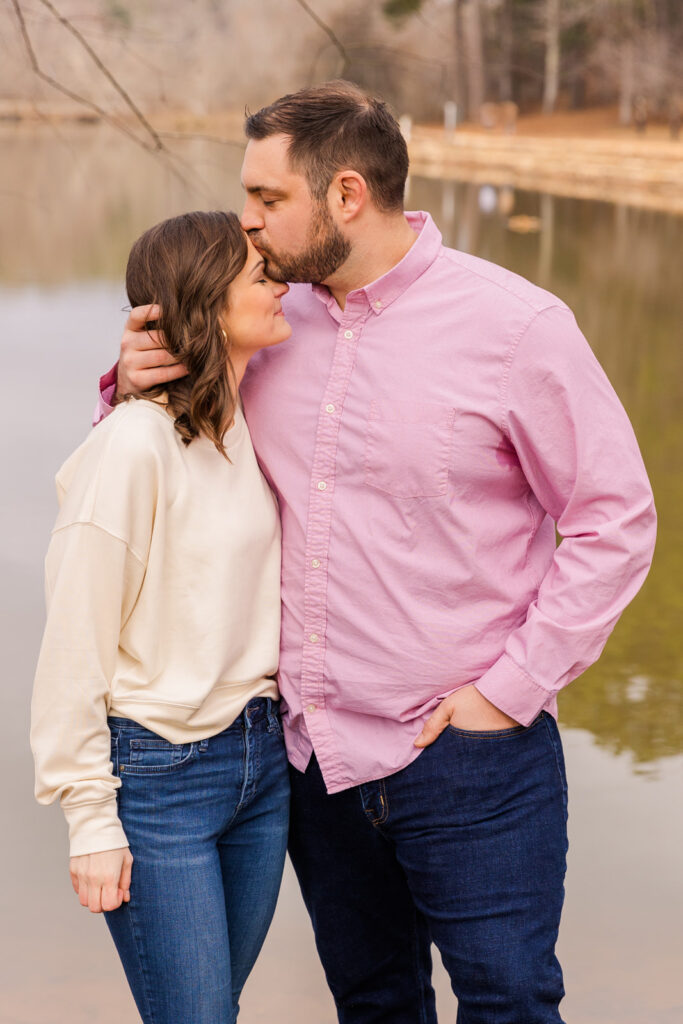 Couple kissing his wife's forehead in front of a pond by Atlanta family photographer Laure Photography