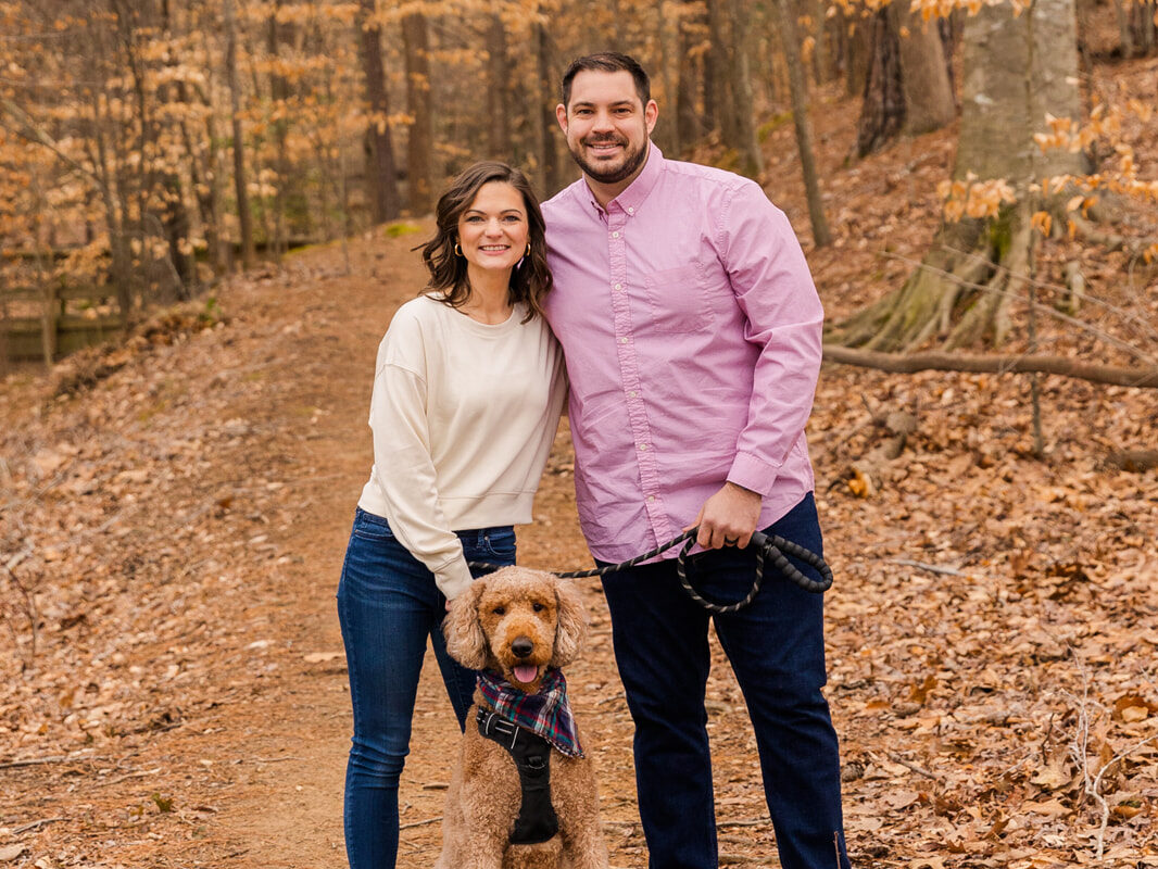 Couple standing with their dog on a wood path during couple photoshoot by Atlanta family photographer Laure Photography