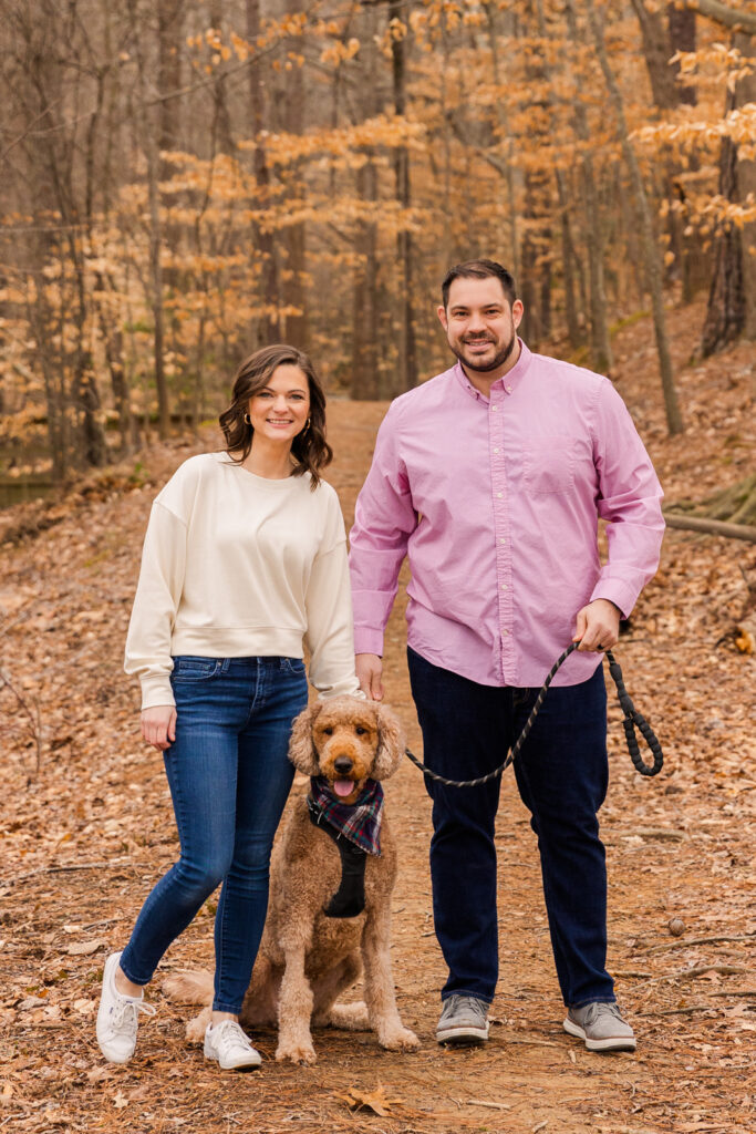 Couple standing with their dog on a wood path during couple photo session by Atlanta family photographer Laure Photography