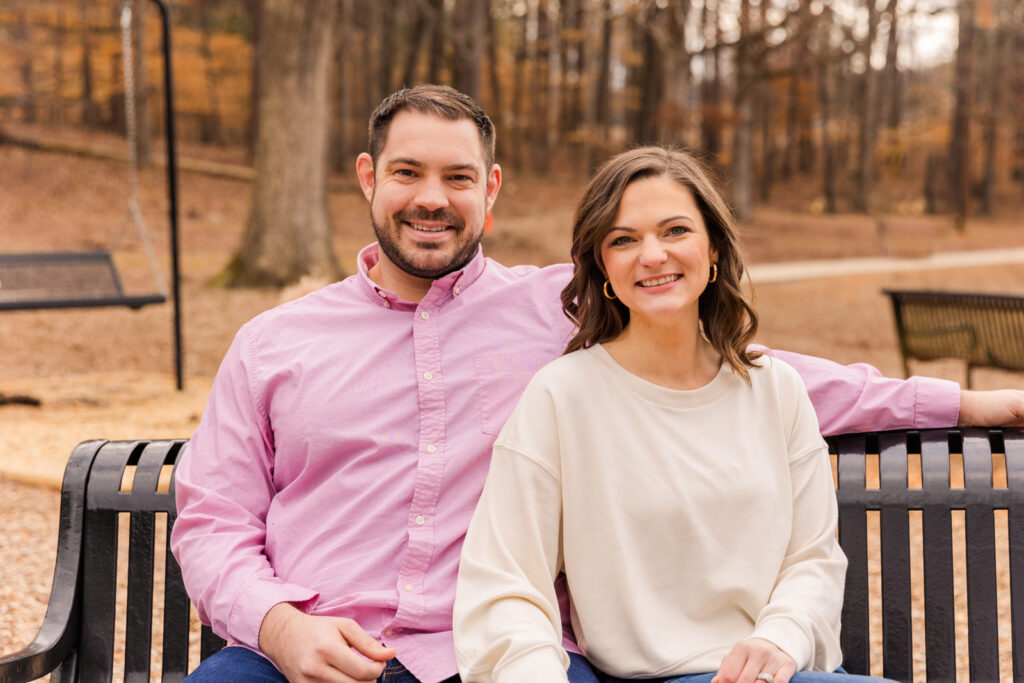 Couple sitting on a park bench in front of woods during a family photoshoot by Atlanta family photographer Laure Photography