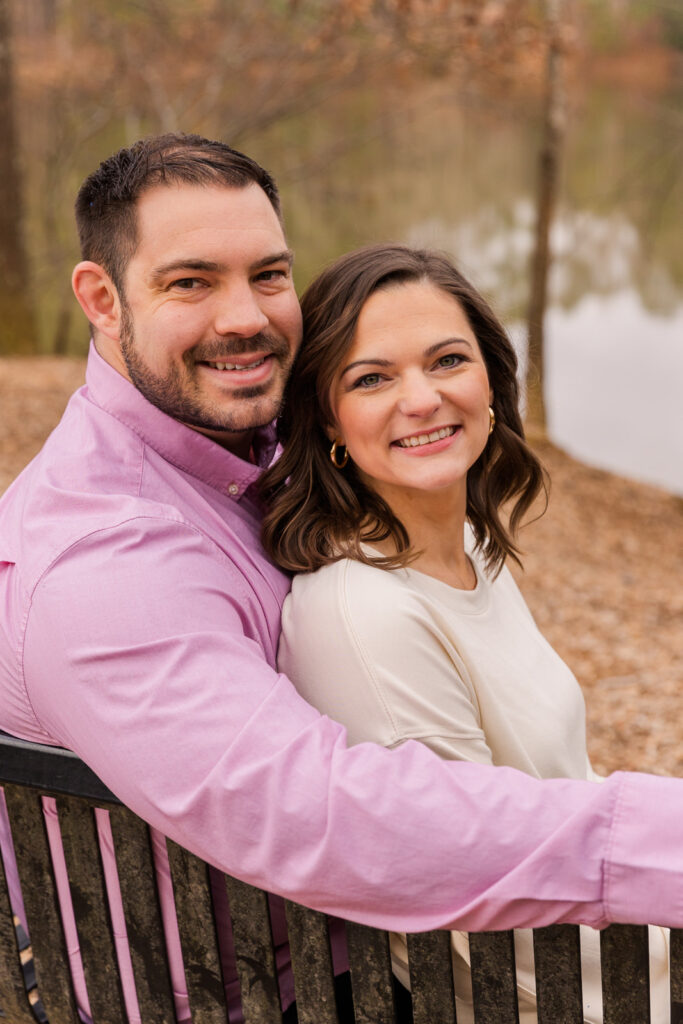 Couple sitting on a bench in front of a park pond during photoshoot by Atlanta family photographer Laure Photography