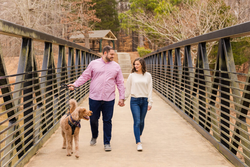 Couple talking hand in hand with their dog on a bridge during photo session by Atlanta family photographer Laure Photography